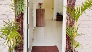 A doorway with a brown mat leading to a room with a wooden cabinet and a small table. - Golden Farms Resorts (Anekal)