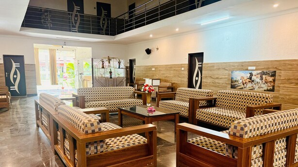 A spacious lobby with checkered sofas, a wooden coffee table, and a staircase. - Golden Farms Resorts (Anekal)