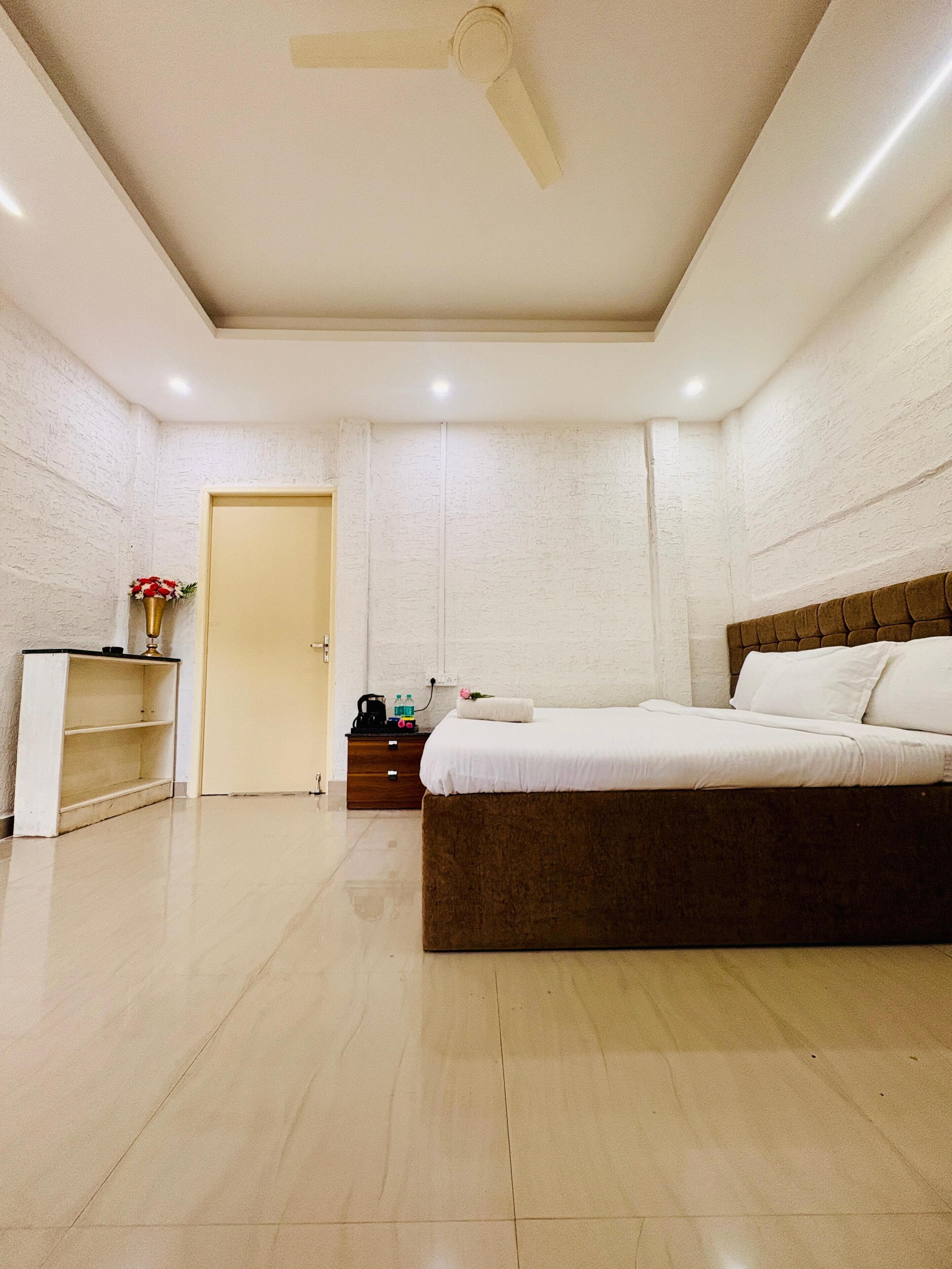 Quarto com cama, mesa de cabeceira, cômoda e ventilador de teto.