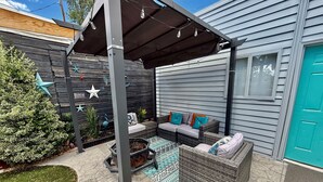 A covered patio area with outdoor furniture, a fire pit, decorative star-shaped ornaments, and a small tree. - Wild Bird Grove – Paws Welcome, Near Downtown SLC (Salt Lake City)