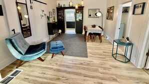 A modern interior with a dining area, a blue chair, a patterned rug, and a wooden floor. - Wild Bird Grove – Paws Welcome, Near Downtown SLC (Salt Lake City)