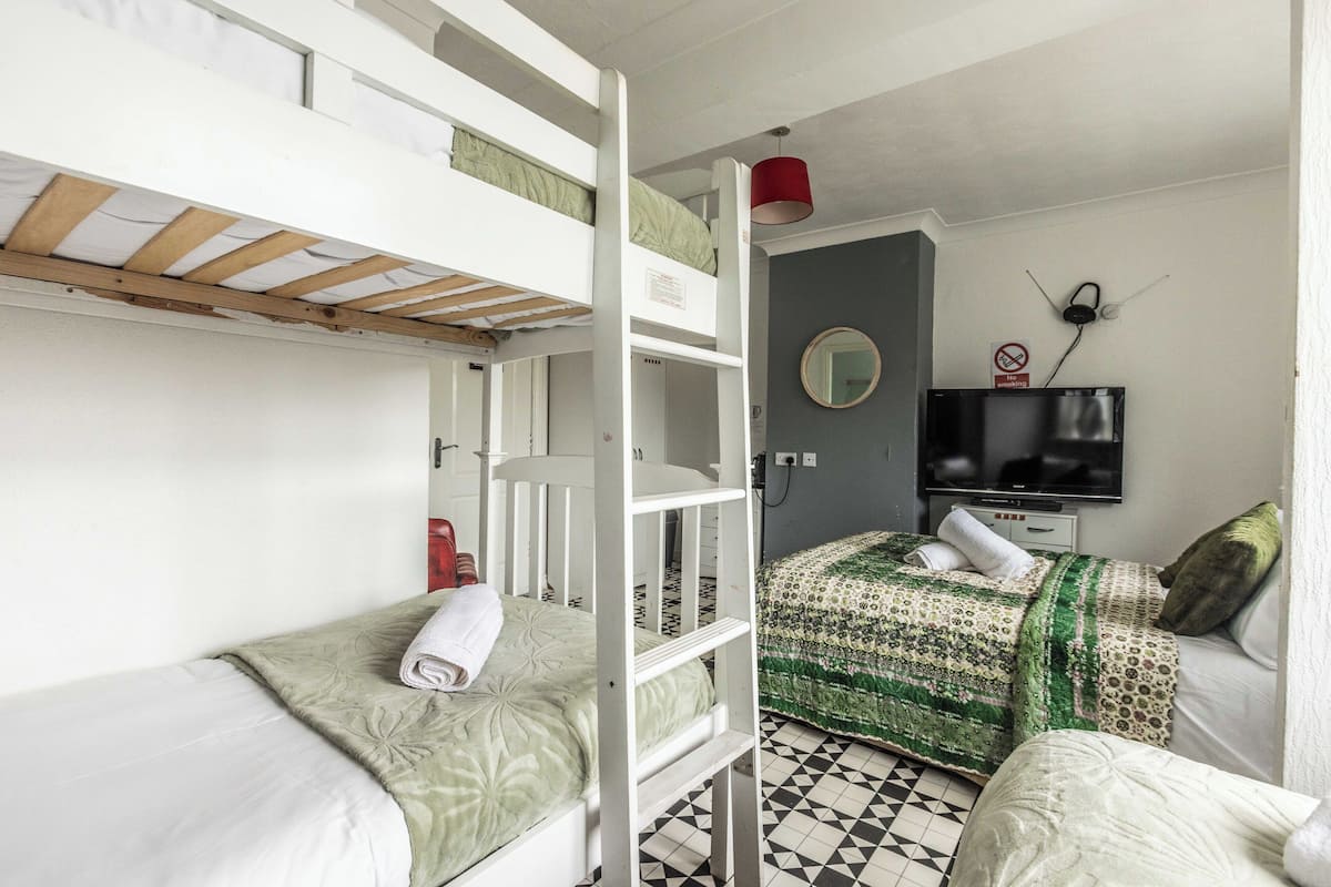 Een studentenkamer met stapelbedden, een televisie en een spiegel aan de muur.