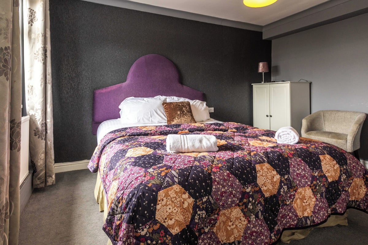 Een slaapkamer met een groot bed, een hoofdbord, een kast en een stoel.