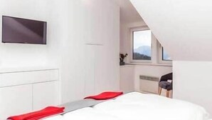 Un dormitorio moderno con cama, televisor de pantalla plana y ventana con vistas.