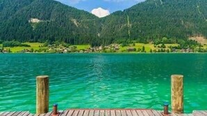 Un lago con un muelle de madera, rodeado de montañas boscosas.