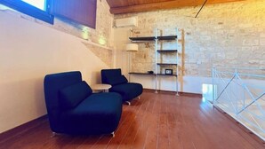 Ein Zimmer mit Steinwand, Holzboden und einem Balkon mit Geländer.