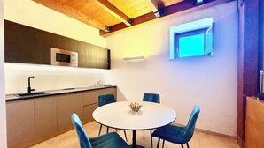 Eine moderne Küche mit weißer Arbeitsplatte, einer eingebauten Mikrowelle und einem runden Tisch mit vier Stühlen.