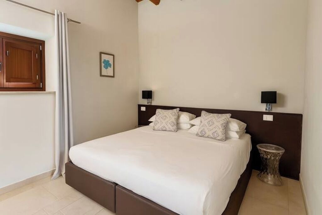 A neatly made bed with a wooden headboard, two bedside lamps, and a small round table beside it.