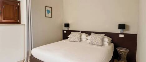A neatly made bed with a wooden headboard, two bedside lamps, and a small round table beside it.