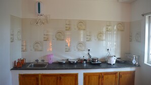 A kitchen with a countertop, sink, and various kitchen appliances. - Pears Garden Royal Suite (Kodaikanal)