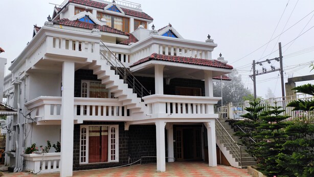 A multi-story building with a central staircase, balconies, and a tiled roof. - Pears Garden Royal Suite (Kodaikanal)