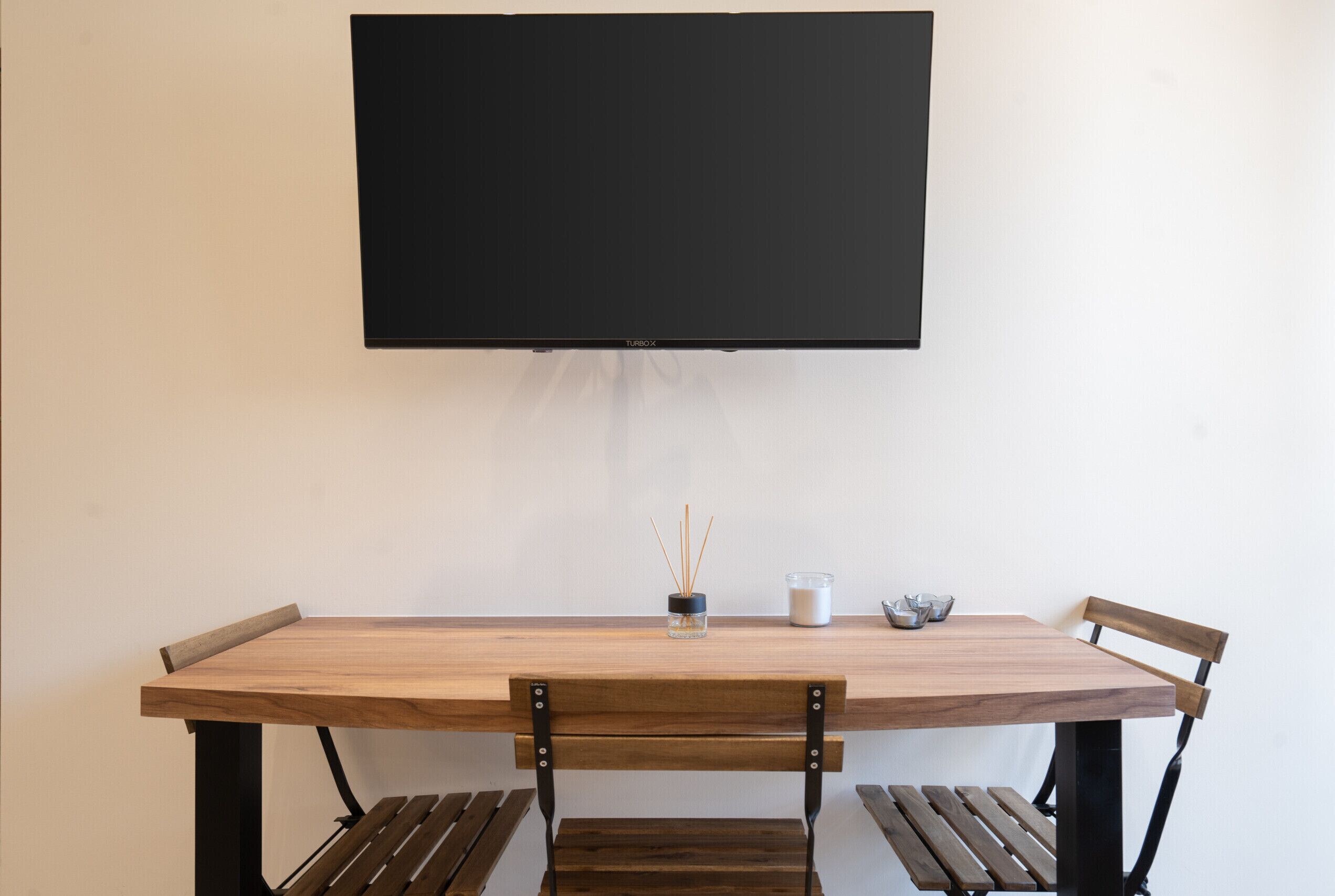 Une table à manger avec un téléviseur à écran plat fixé au mur au-dessus.