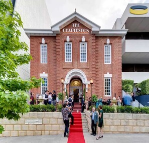 A brick building with 'The Charleston' sign, a red carpet, and people gathered outside. - Stylish 1BR APT in West Perth with Parking! (West Perth)