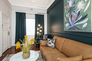 A living room with a brown sofa, a round coffee table, and a painting on the wall.