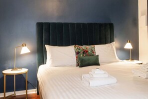 A neatly made bed with white linens, a dark headboard, and two bedside lamps.