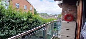 Un balcon avec une balustrade en verre, une guirlande rouge et un mur en briques.