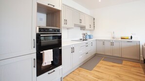 A modern kitchen with white cabinets, a built-in oven, and a wooden countertop. - Modern 3BD Split-Level Home with Balcony,Dublin 16 (Dublin)