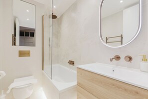 Ein modernes Badezimmer mit einer Duschkabine aus Glas, einer weißen Badewanne und einem Waschtisch mit Holzschrank.