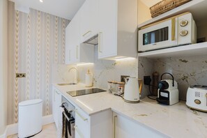 Eine moderne Küche mit weißen Schränken, einer Marmorarbeitsplatte, einer Spüle, einem Toaster und einer Mikrowelle.