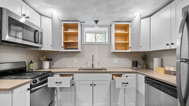 A modern kitchen with white cabinets, a stainless steel stove, a microwave, and a dishwasher. - Charming 1BR apt -close to public transit -has parking -30min drive to BOS/Salem (Reading)