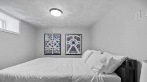 A bedroom with a bed, a nightstand, a lamp, and two framed wall art pieces. - Charming 1BR apt -close to public transit -has parking -30min drive to BOS/Salem (Reading)