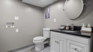 A modern bathroom with a toilet, vanity, and a large mirror. - Charming 1BR apt -close to public transit -has parking -30min drive to BOS/Salem (Reading)