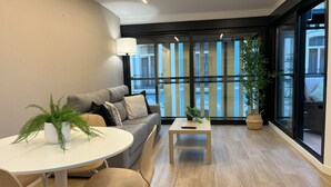 Una sala de estar moderna con un sofá gris, una mesa redonda blanca y una planta en maceta.