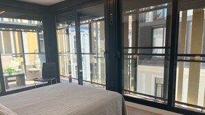 Un dormitorio con una cama grande, una ventana con persianas y vistas al exterior.