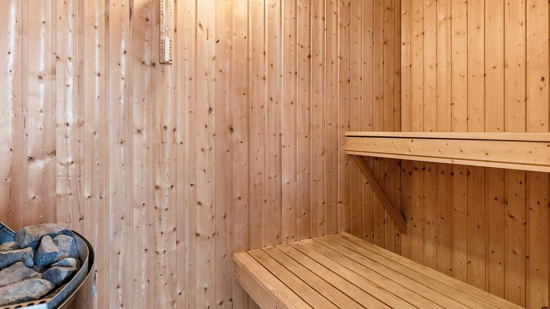 Un sauna avec des murs en bois, un banc et un récipient en métal rempli de pierres.