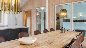 Un comedor moderno con una mesa de madera, sillas y una lámpara colgante.