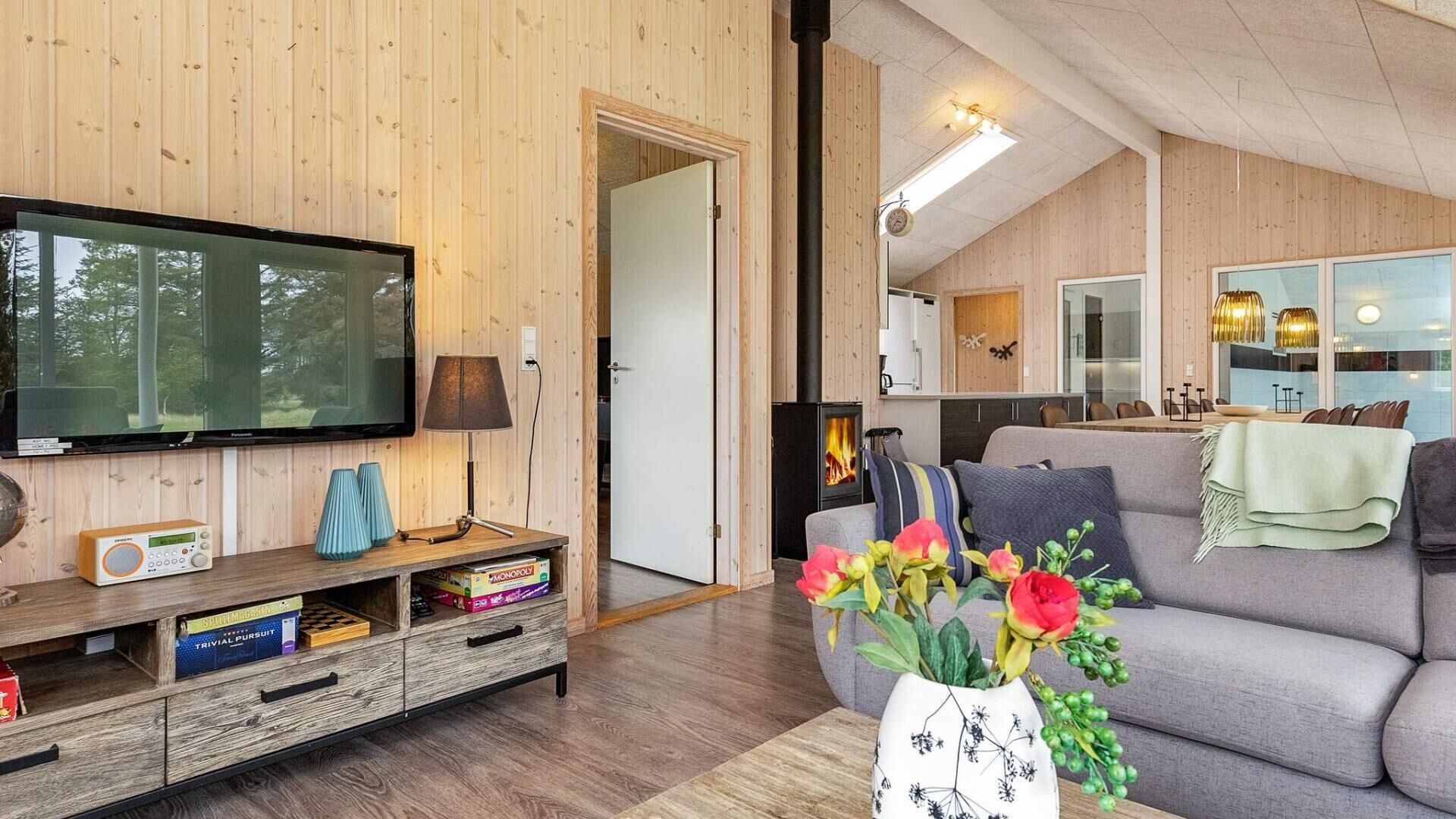 Una sala de estar acogedora con televisor, chimenea, sofá y un jarrón de flores.