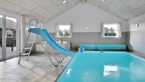 A swimming pool with a slide, a bench, and a small table with a bottle. - VillaVilla 194 - Nr. Lyngby ved Løkken, nordjyllan (Løkken)