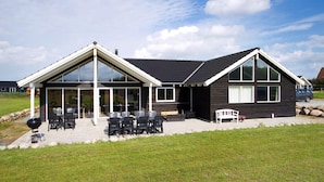Une maison moderne dotée d’un patio aménagé avec du mobilier d’extérieur et un barbecue.