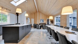 Une cuisine moderne dotée d’un grand îlot central, de meubles de couleur noire et de luminaires suspendus.