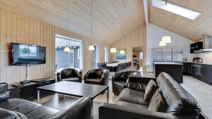 Un intérieur moderne avec un plafond en bois, un coin repas, une cuisine et des meubles en cuir.