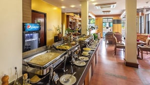 A buffet area with various food options, a Pepsi refrigerator, and seating arrangements. - Paundur Community Homestay (Pokhara)