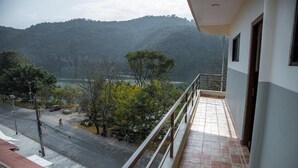 A balcony with a view of a road and trees, overlooking a hilly landscape. - Paundur Community Homestay (Pokhara)