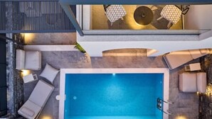 Ένας χώρος πισίνας στην ταράτσα, με υδρομασάζ, ξαπλώστρες και μια περιοχή με τραπέζι και καρέκλες για να καθίσετε.