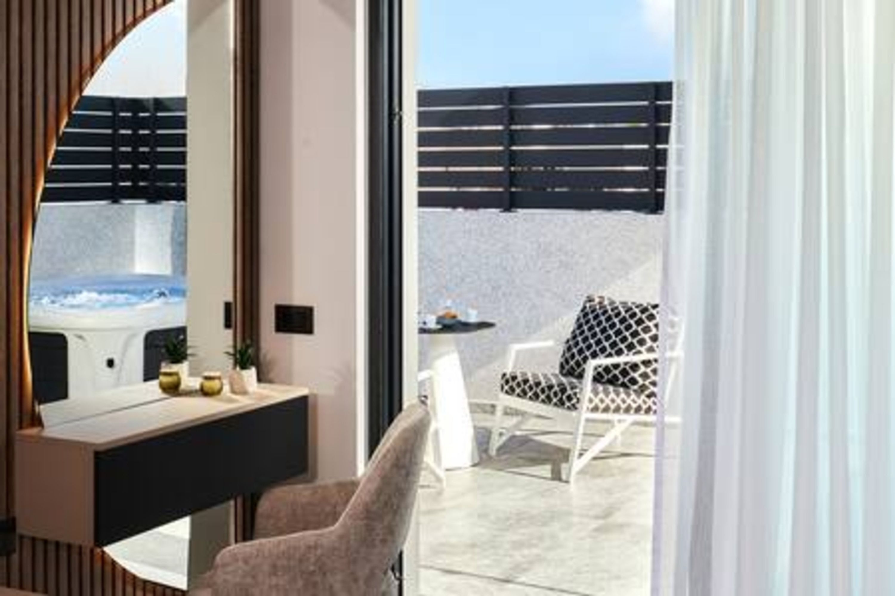 Une salle de bain moderne avec un grand miroir, un meuble-lavabo et une vue sur la terrasse extérieure.