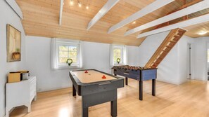 A spacious room with wooden flooring, two foosball tables, a white dresser, and a staircase. - VillaVilla 145 - Vester Husby, Vestjylland (Ulfborg)