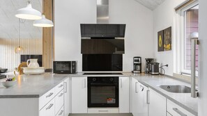 A modern kitchen with white cabinetry, a built-in oven, a microwave, and a coffee maker. - VillaVilla 286 - Nordals, Sydjylland (Nordborg)