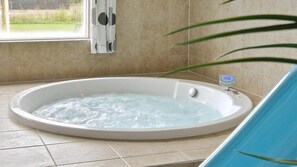 Une salle de bain moderne dotée d’une grande baignoire ovale, d’un système de contrôle numérique de la température de l’eau et offrant une vue sur l’extérieur grâce à une fenêtre.