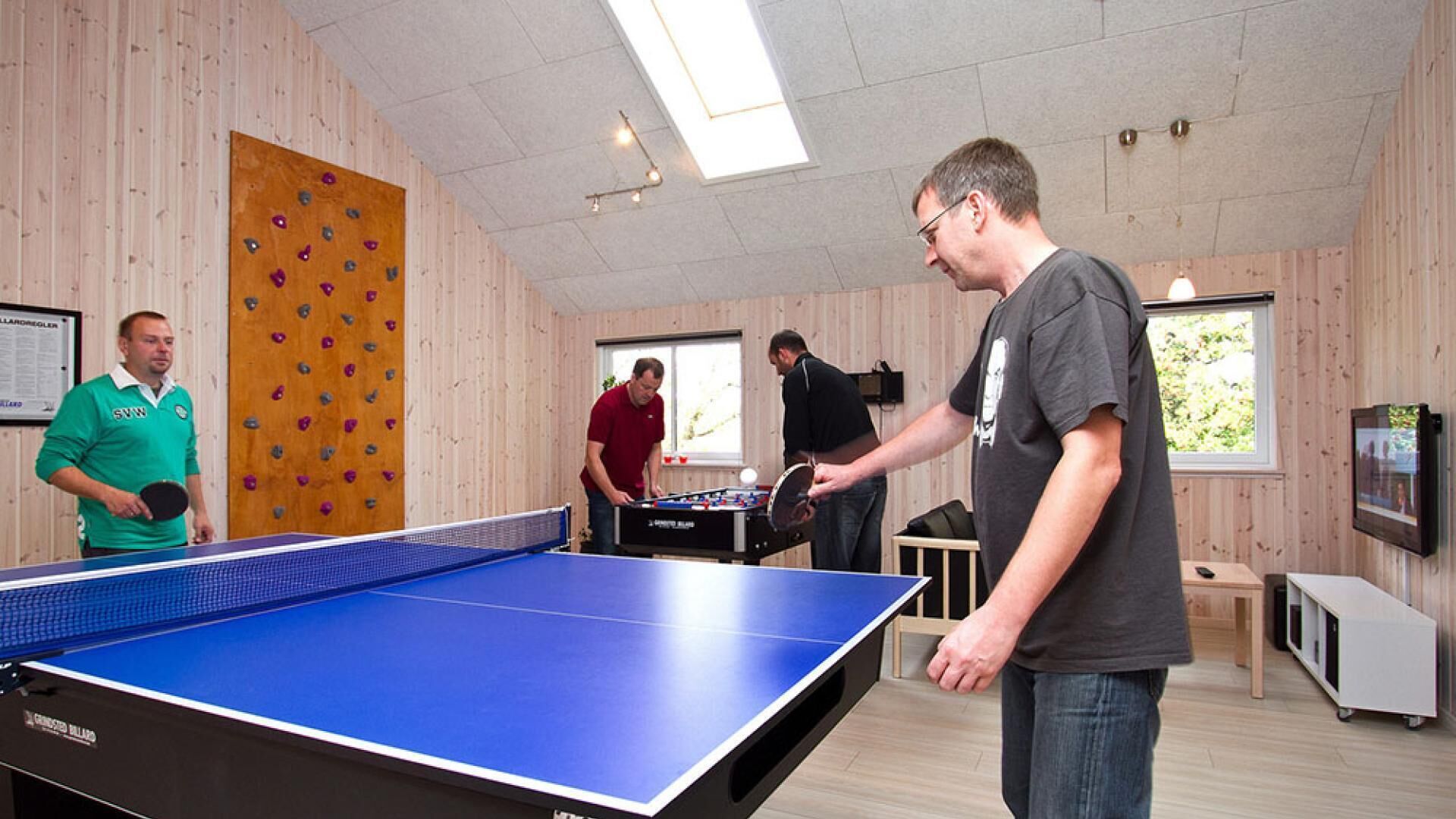 Una stanza con tavolo da ping pong, tavolo da calcio e parete da arrampicata.