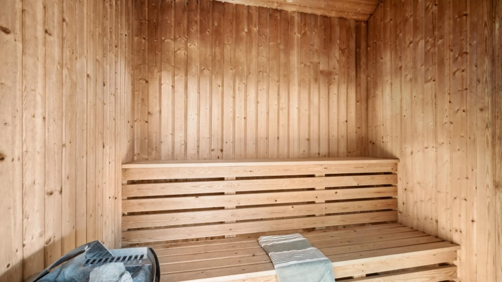 Un sauna en bois avec des bancs et un banc muni d’une serviette.