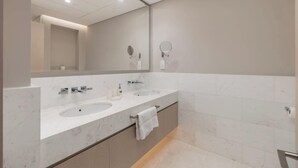 Un baño moderno con dos lavamanos, un espejo grande y un perchero para toallas.
