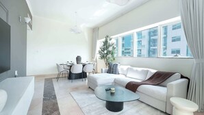 Ein modernes Wohnzimmer mit einem weißen Sofa, einem runden Couchtisch und einem Essbereich mit Tisch und Stühlen.