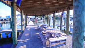 A covered dock with wooden picnic tables and benches, wooden pillars, and a view of the water and marina in the background. - Bayview Freedom (Orange Beach)