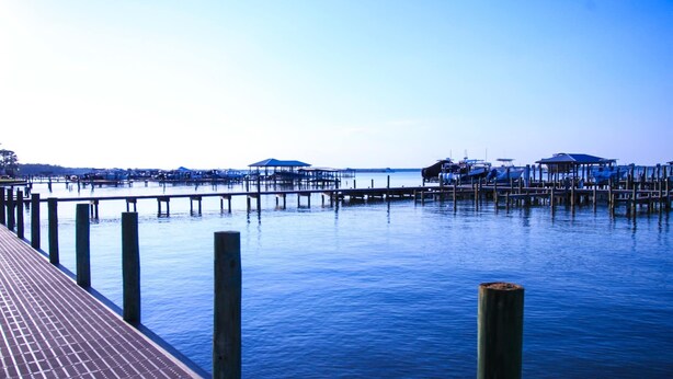 A pier extending into calm water with wooden posts and a brick walkway. - Bayview Freedom (Orange Beach)