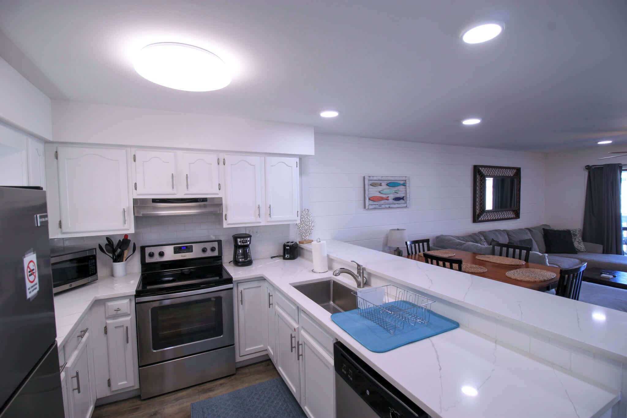 A modern kitchen with white cabinets, stainless steel appliances, and a dining area with a table and chairs.