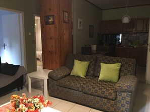 A living room with a patterned sofa, a small table, and a floral arrangement.